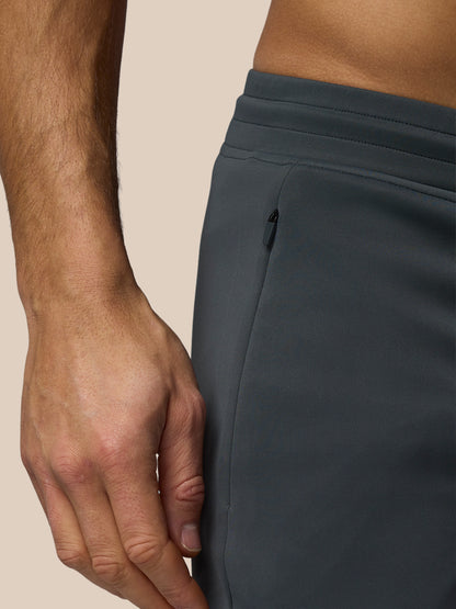 Close-up of a person wearing dark gray pants with a neutral background