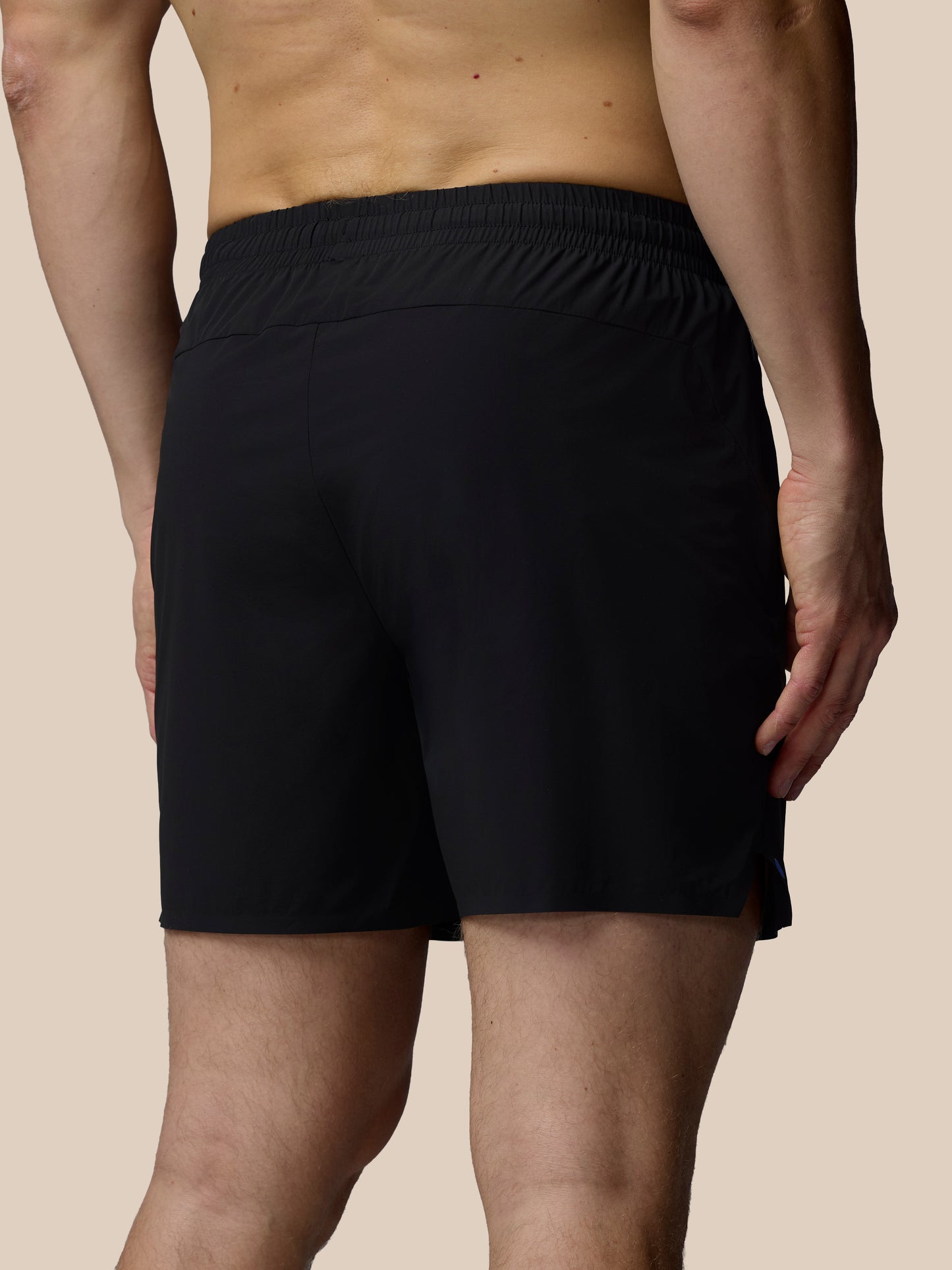 Person wearing black shorts on a beige background