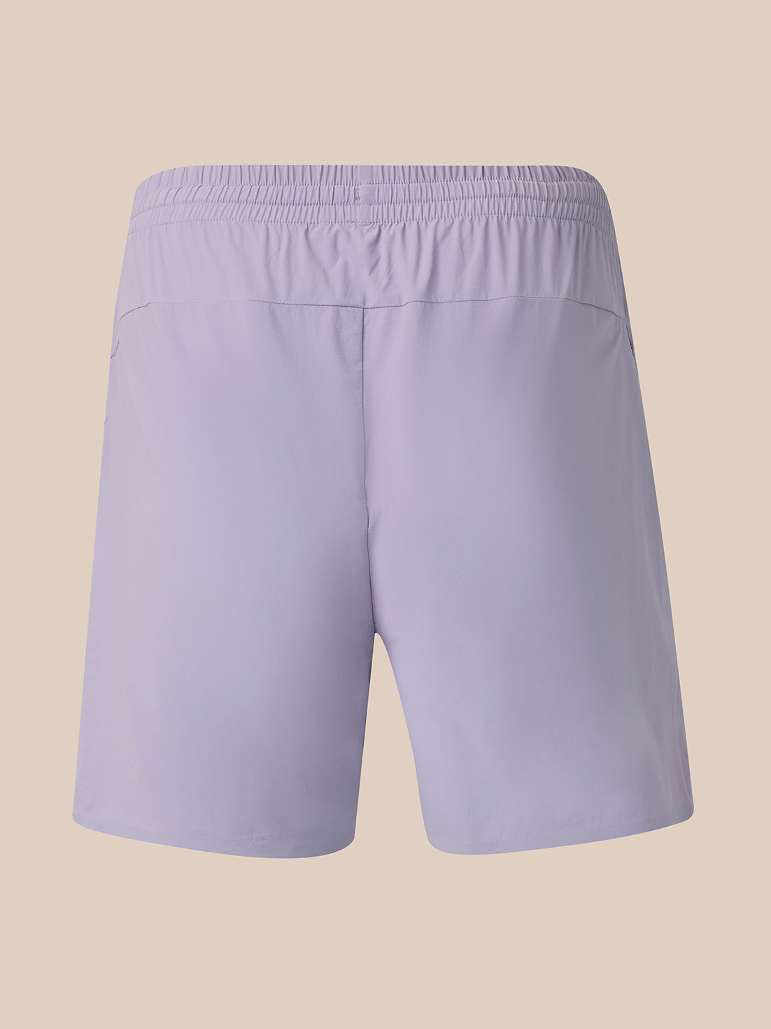 Light lavender athletic shorts with an elastic waistband, shown from the back on a solid beige background.
