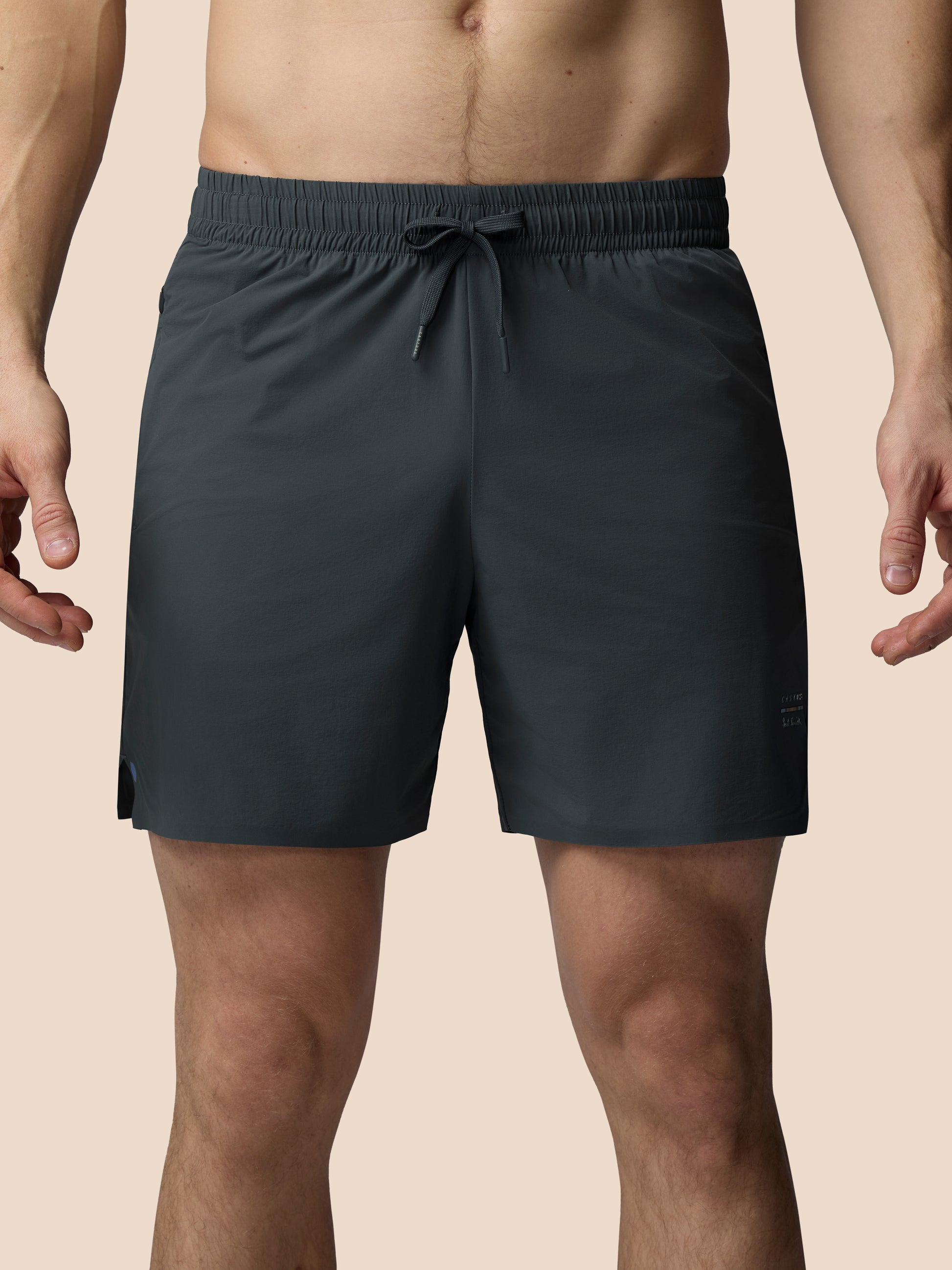 Dark gray shorts worn by a person on a beige background
