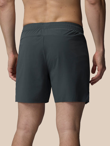 Person wearing dark gray shorts on a beige background