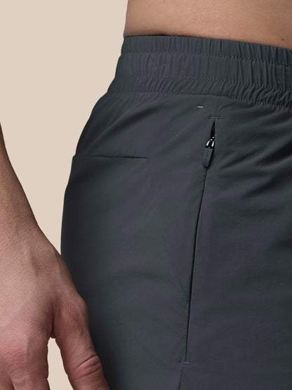 Dark gray athletic pants with a zipper pocket on a beige background