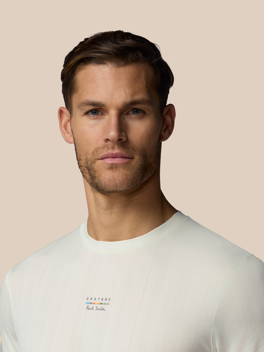Man wearing a light gray t-shirt against a beige background