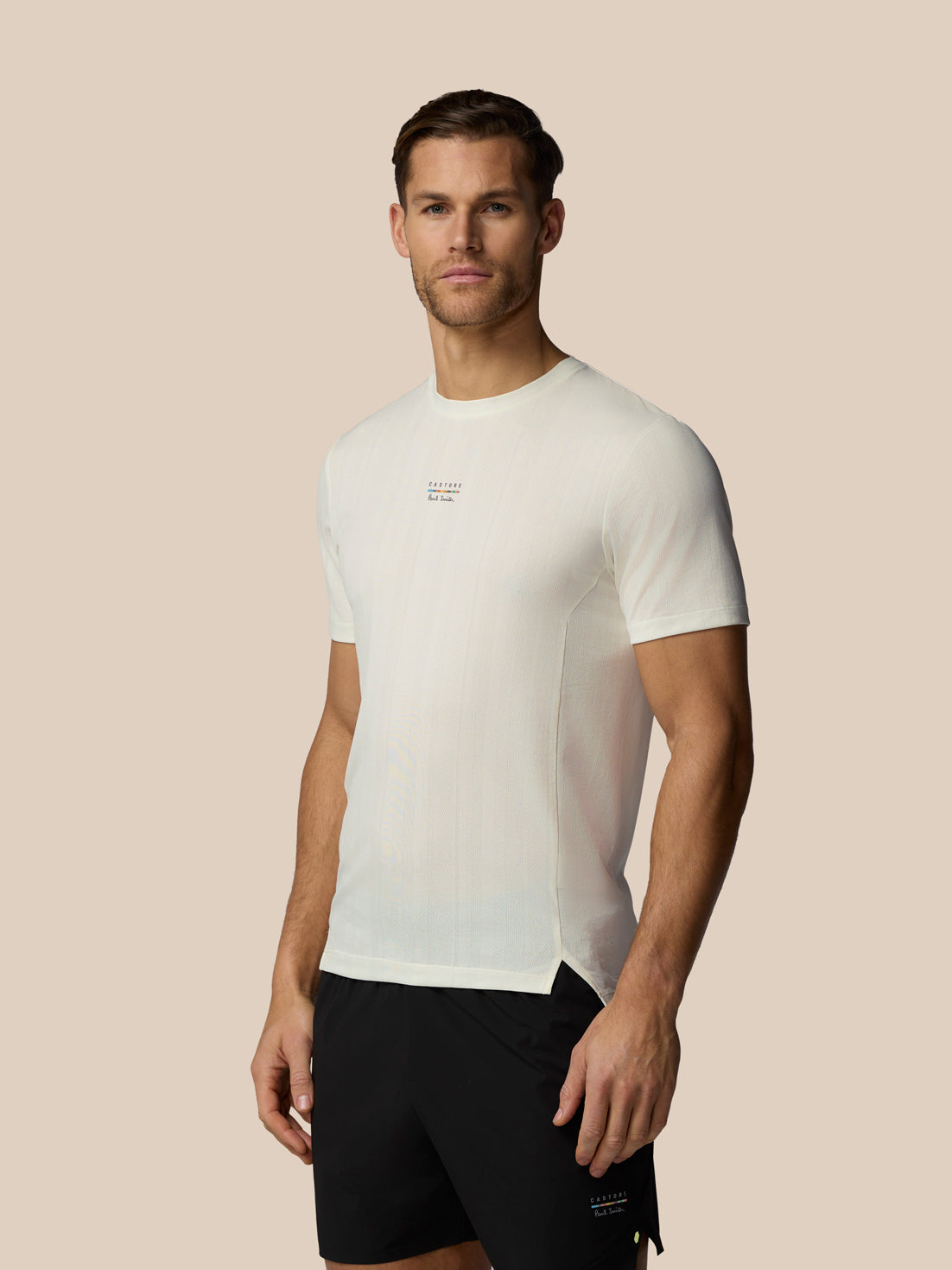 Man wearing a white t-shirt with a small logo on a beige background