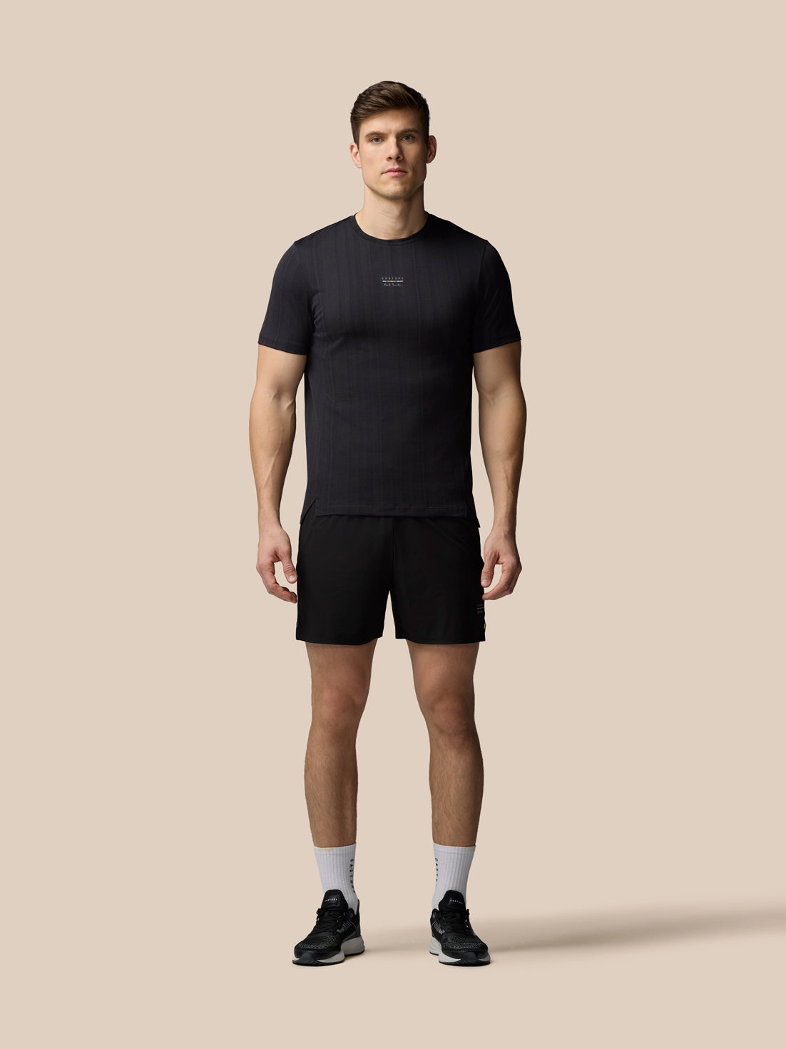 Man wearing a black t-shirt and shorts on a beige background