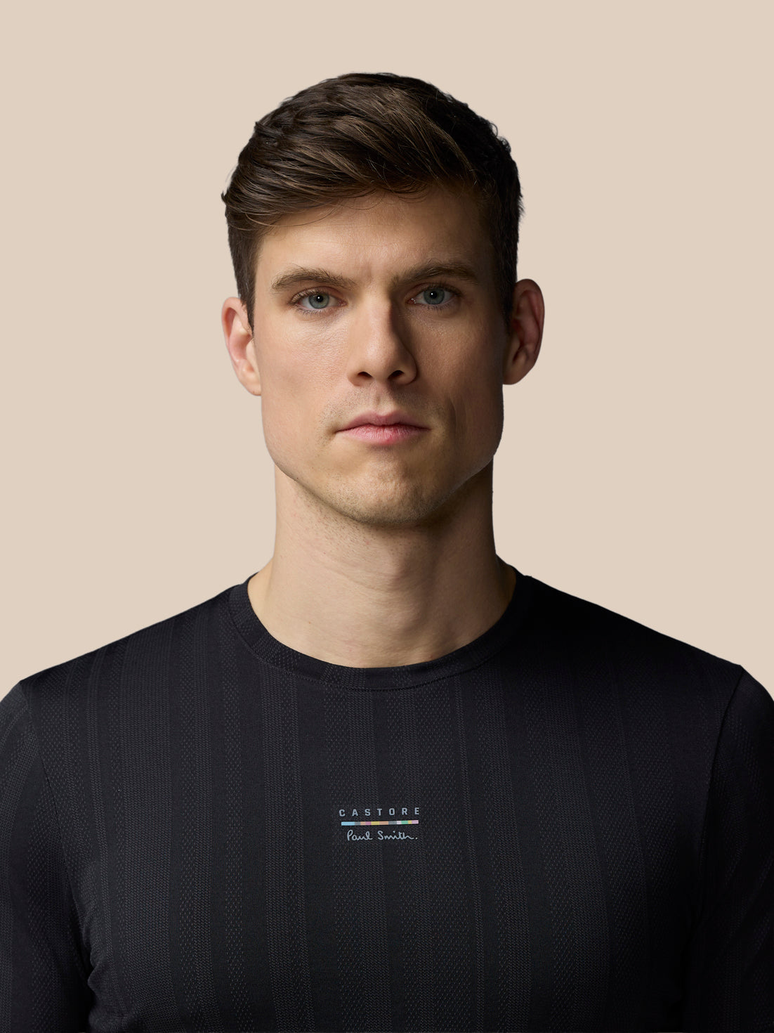 Man wearing a black t-shirt with a logo on a beige background