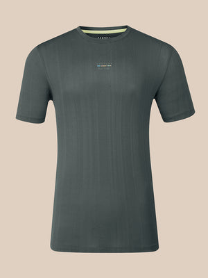 A dark gray short-sleeve crewneck t-shirt with a subtle vertical ribbed texture and a small multicolor logo on the left chest, displayed against a solid beige background.
