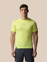 Man wearing a bright yellow t-shirt with a small logo on a beige background
