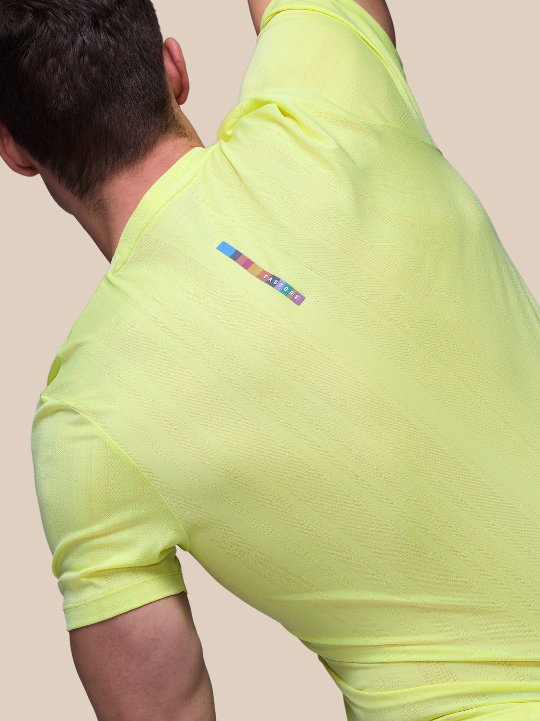 Person wearing a bright yellow athletic outfit with a brand logo on a plain background