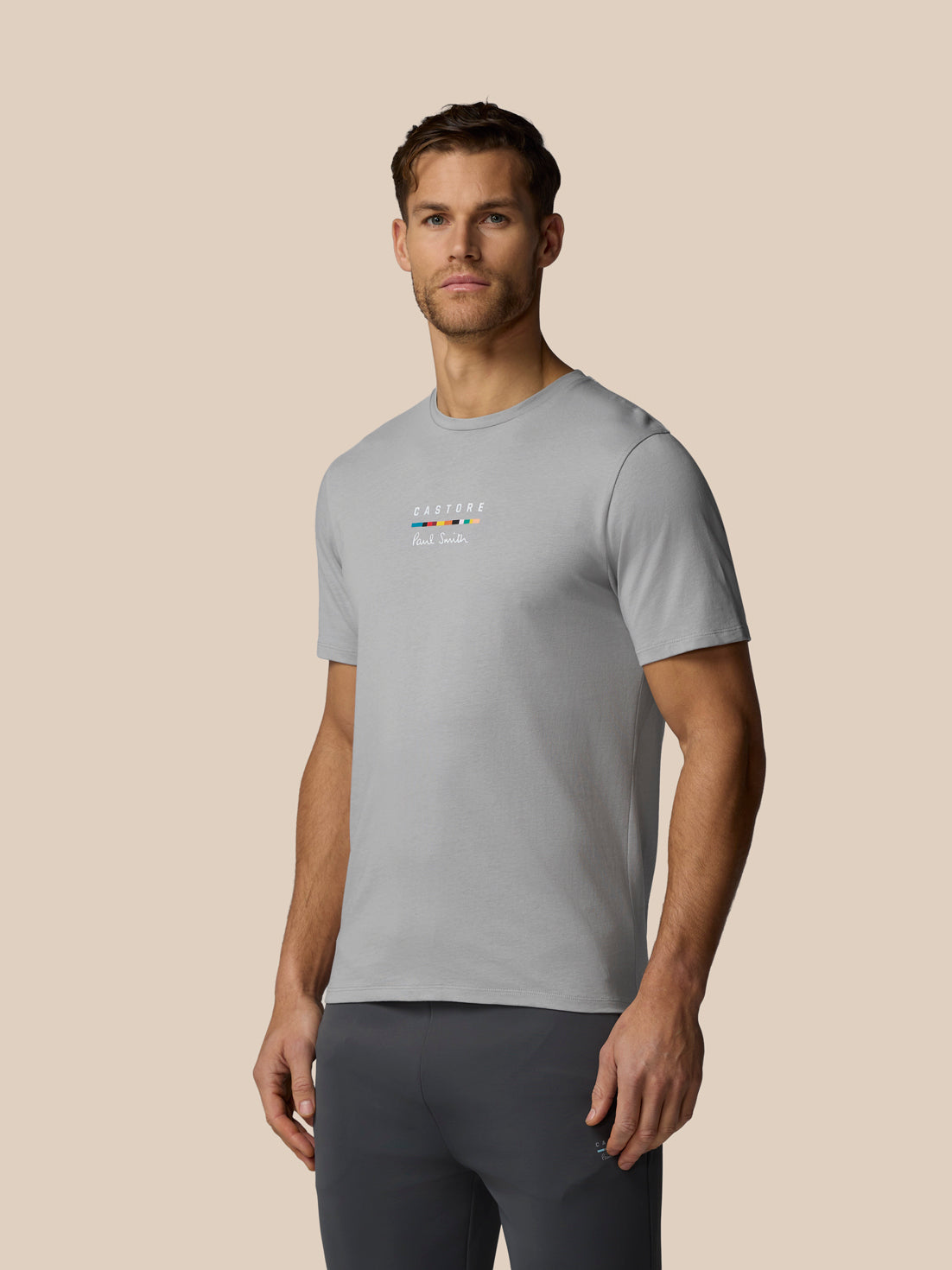 Man wearing a gray t-shirt with a logo on a beige background