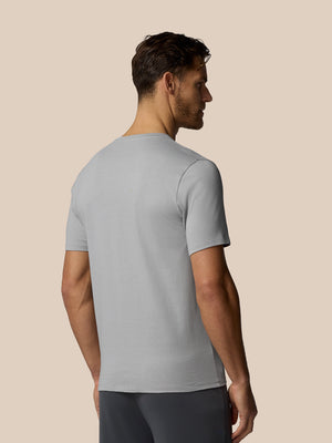Man wearing a light gray t-shirt against a beige background
