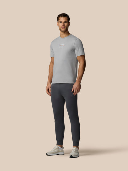 Man wearing a gray t-shirt and dark pants on a beige background