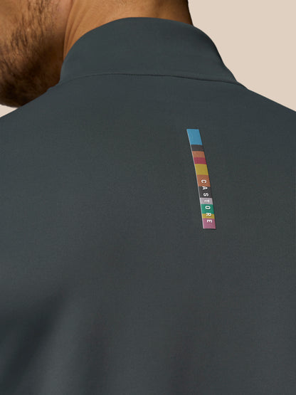 Dark gray jacket with a colorful brand logo on the back against a beige background