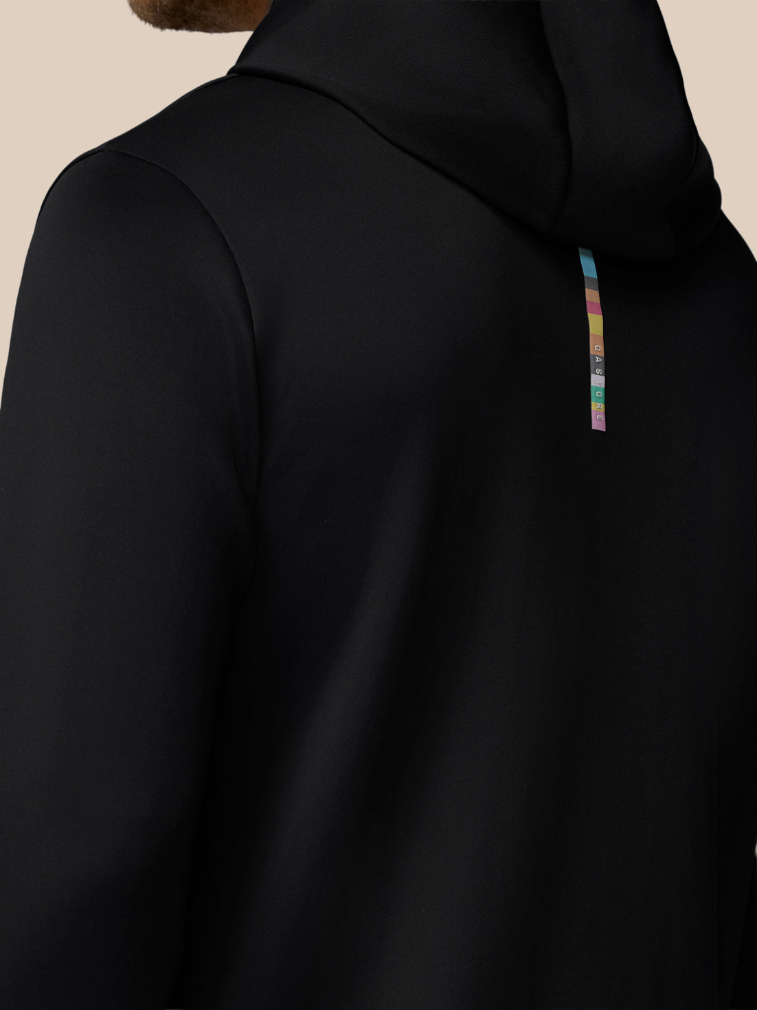 Black hoodie with a colorful logo on the chest against a beige background