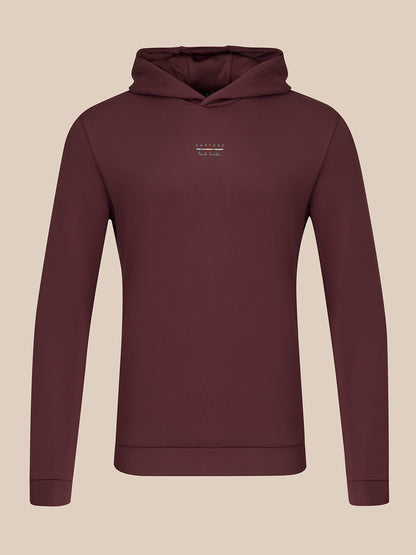 A dark plum-colored long-sleeve hoodie with a small white embroidered logo on the left chest, displayed on a neutral beige background.