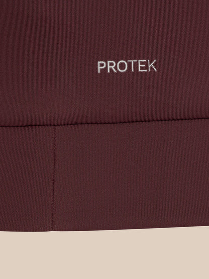 Close-up of a dark burgundy ribbed fabric with the word PROTEK embroidered in white near the top, set against a light beige background.