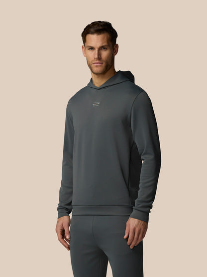 Man wearing a dark gray hoodie and pants on a beige background