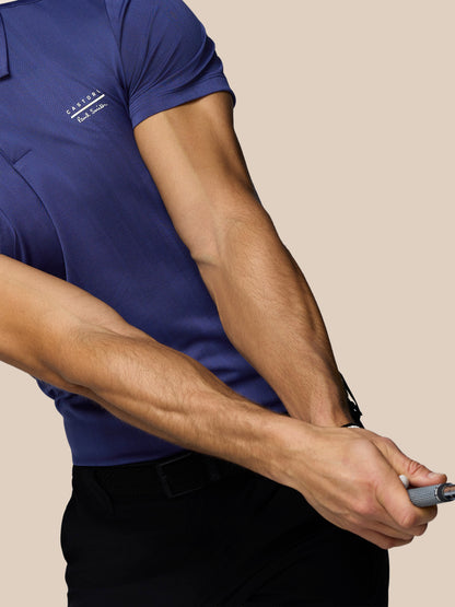 Man wearing a blue polo shirt with a logo on a beige background