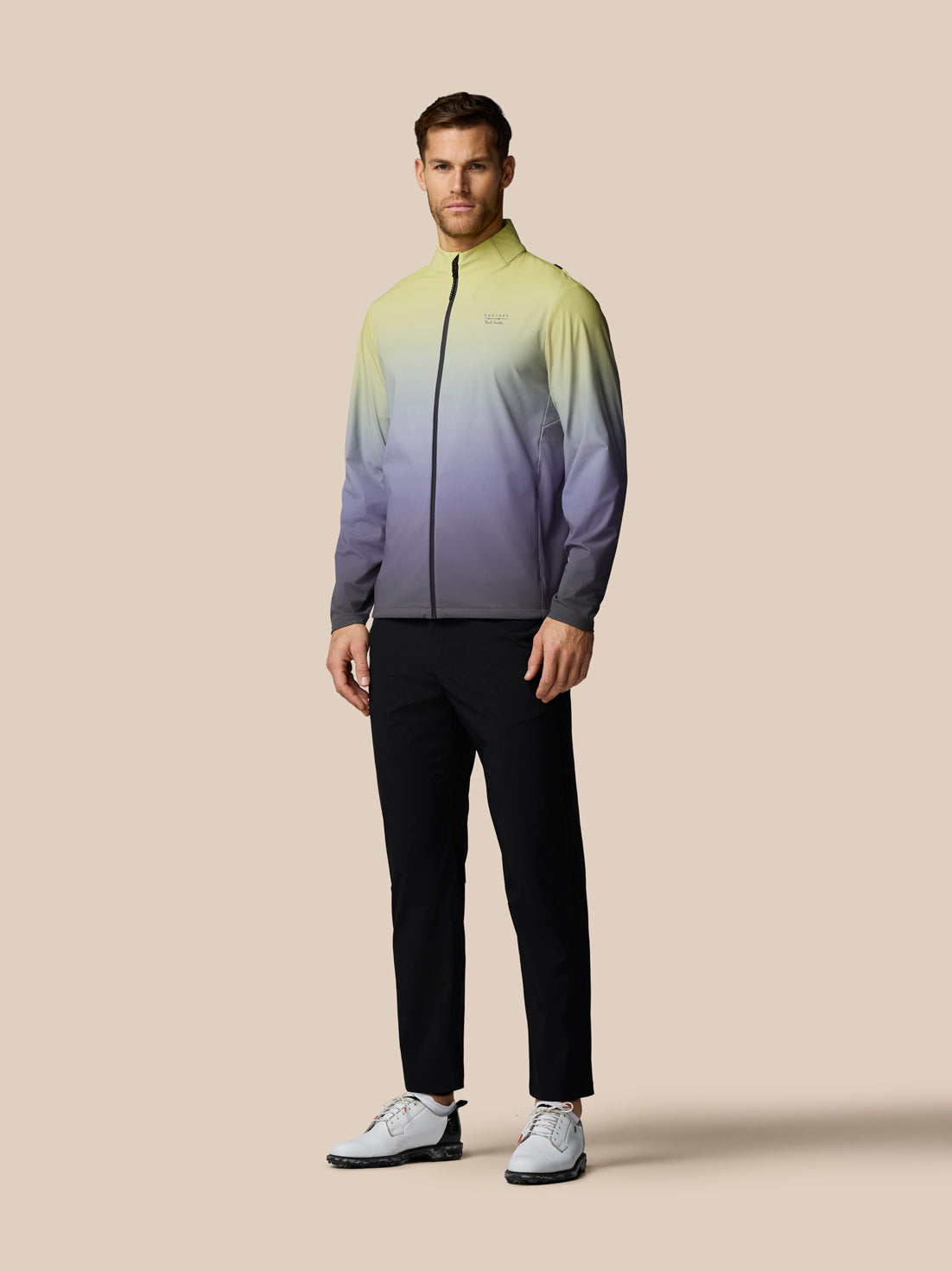 Man wearing a gradient jacket and black pants on a beige background