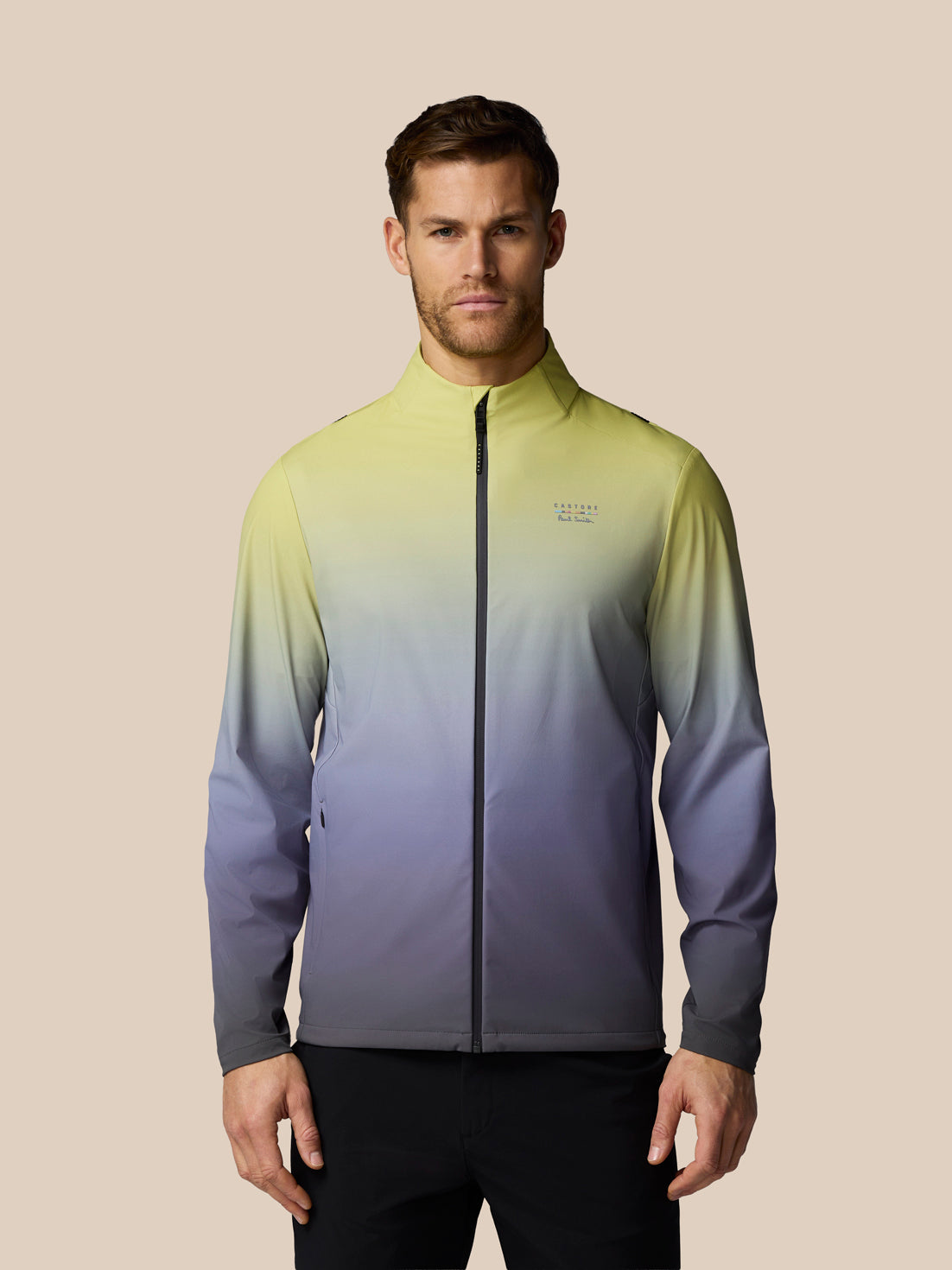 Man wearing a gradient jacket with a brand logo on a beige background