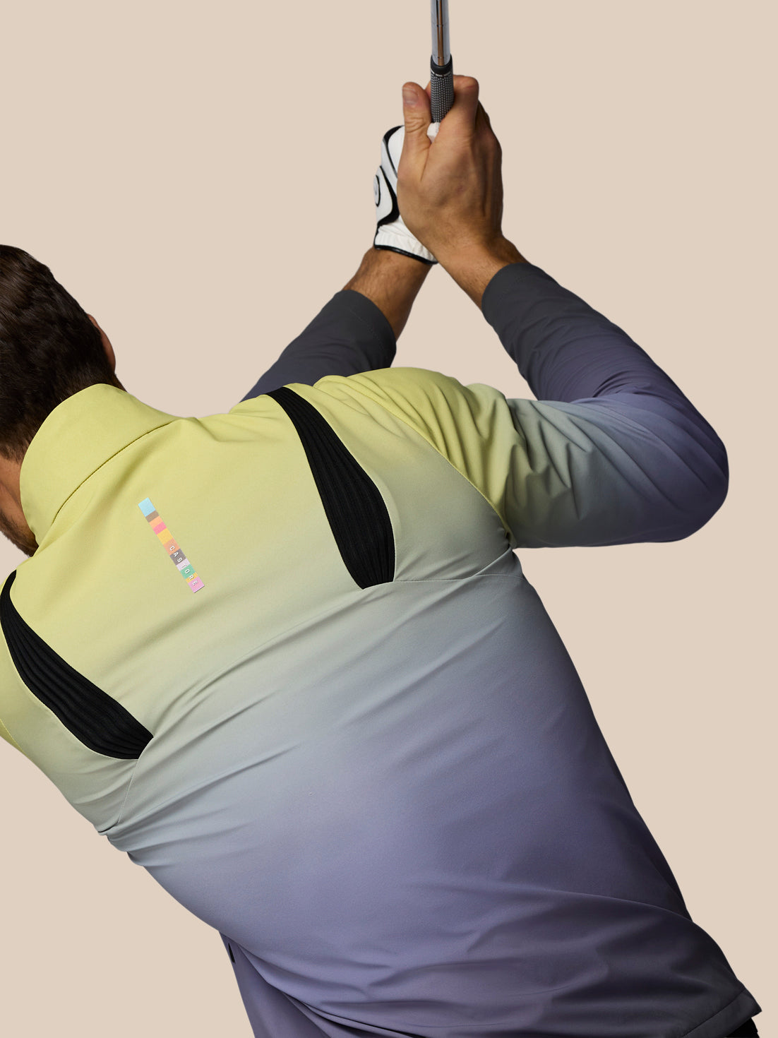 Person in a gradient shirt swinging a golf club against a beige background