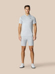 Man wearing light grey golf polo and matching shorts with Castore logo on chest against a beige backdrop