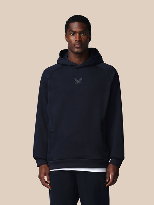 Man wearing a navy hoodie with a logo on a beige background
