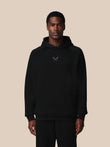 Man wearing a black hoodie with a logo on a beige background