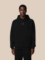 Man wearing a black hoodie with a logo on a beige background