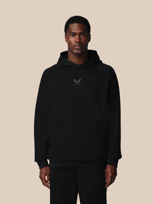 Man wearing a black hoodie with a logo on a beige background