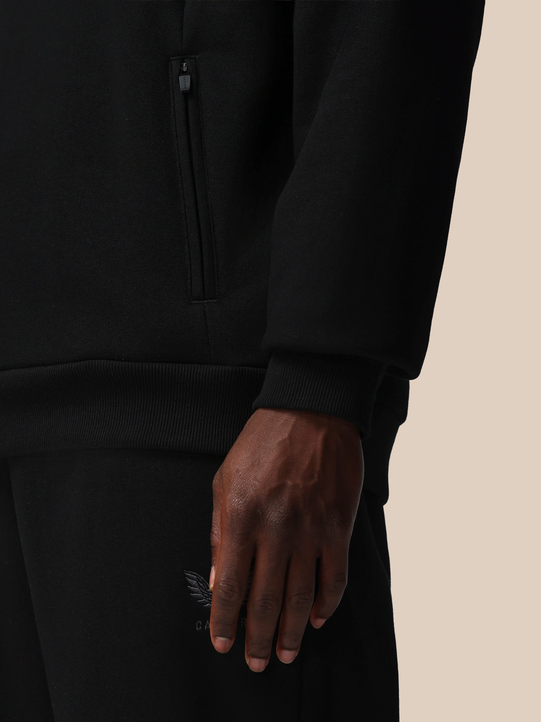 Close-up of a person wearing a black outfit with a beige background
