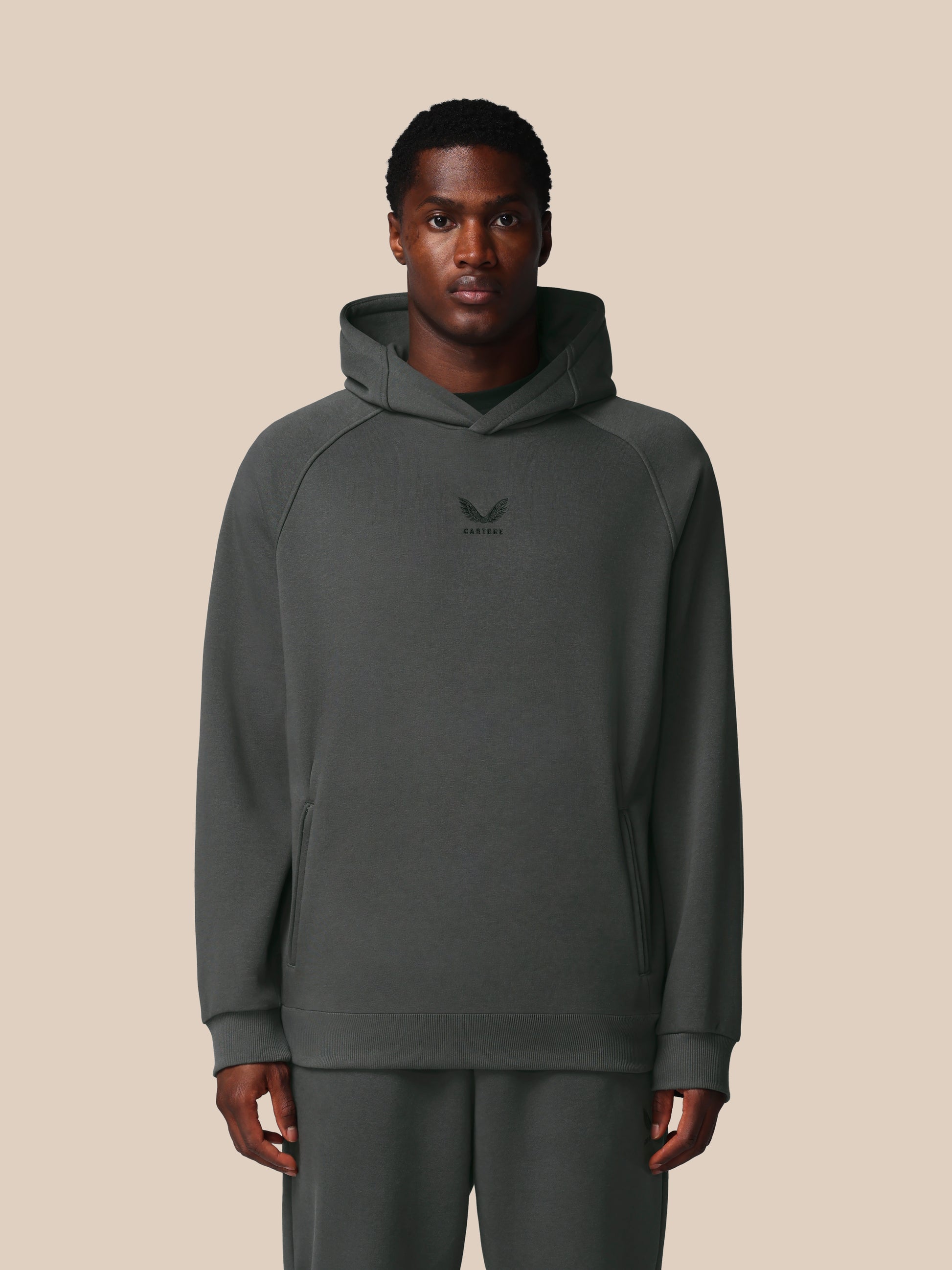 Man wearing a gray hoodie with a logo on a beige background