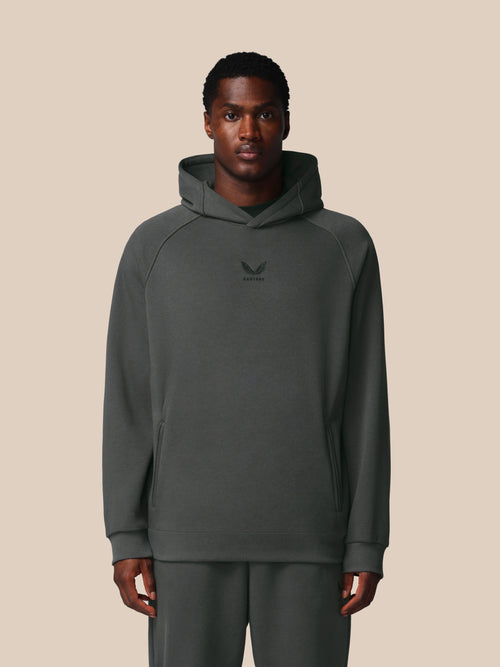 Man wearing a gray hoodie with a logo on a beige background