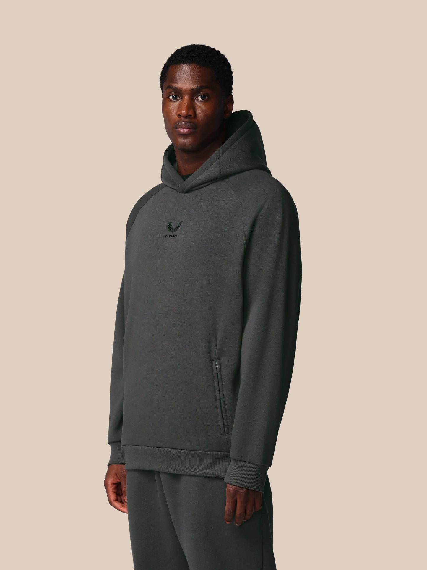 Man wearing a gray hoodie with a logo on a beige background
