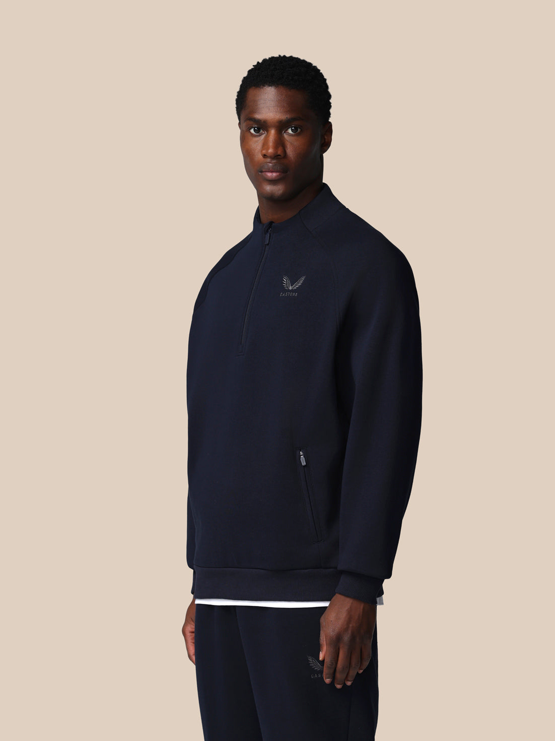 Man wearing a dark blue pullover with a logo on a beige background