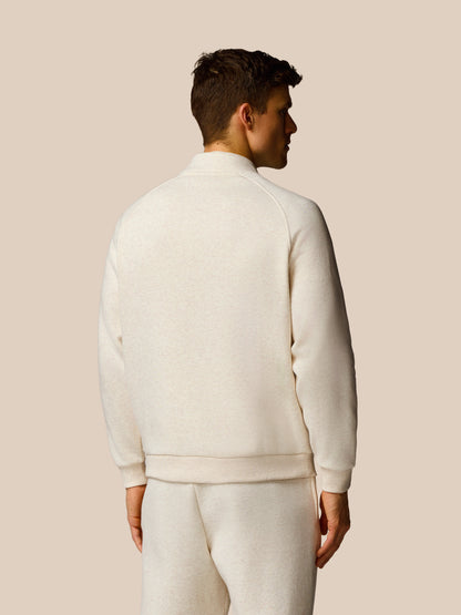 Man wearing a cream-colored tracksuit against a beige background