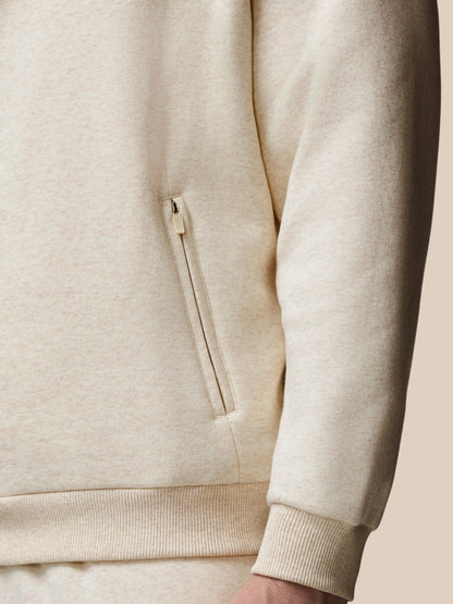 Close-up of a beige hoodie with a zipper pocket on a neutral background