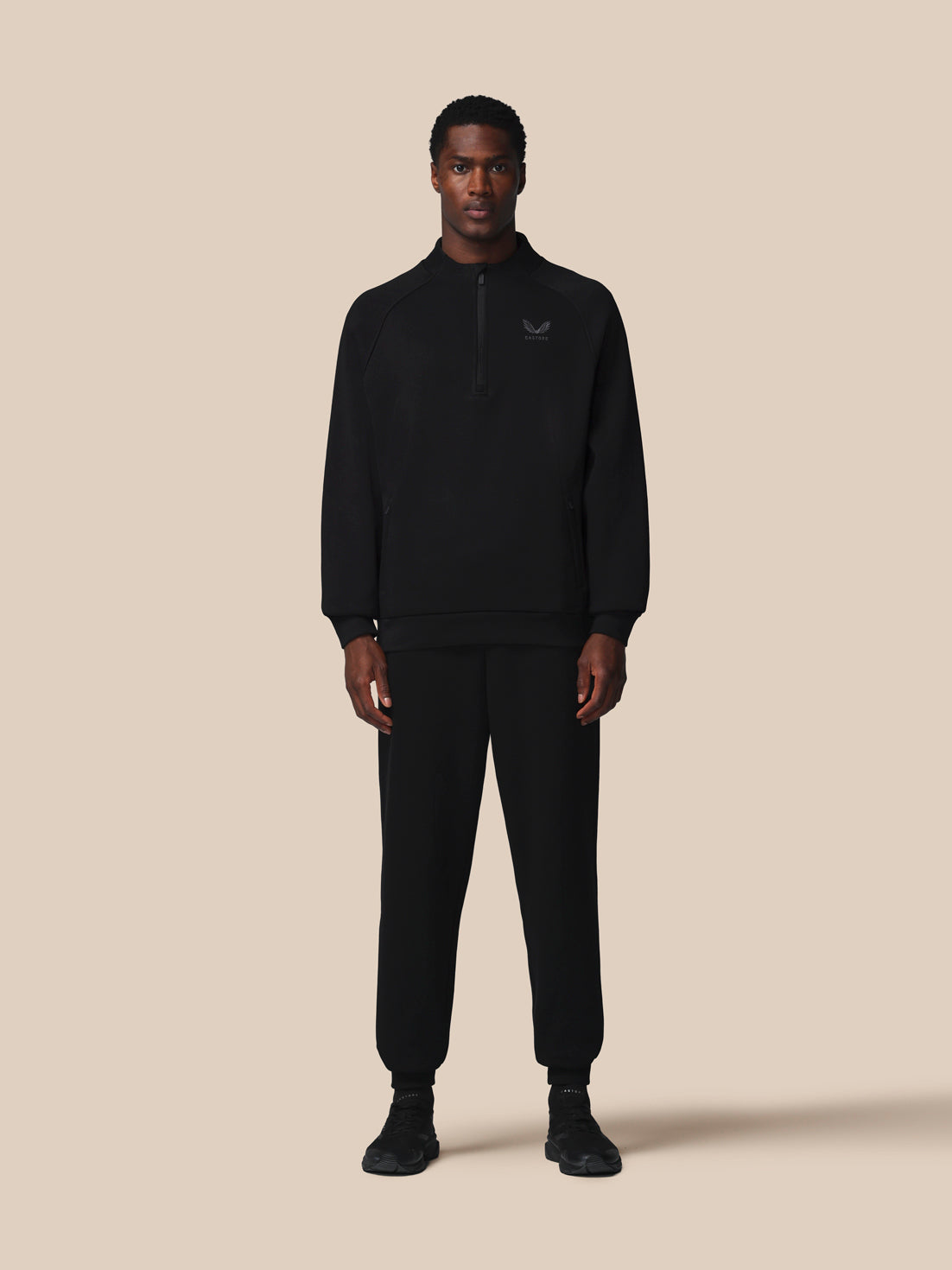 Man wearing a black tracksuit on a beige background