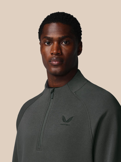 Man wearing a dark gray pullover with a logo on a beige background