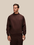 Man wearing a brown Adapt Cotton Fleece quarter zip sweatshirt with stand collar.