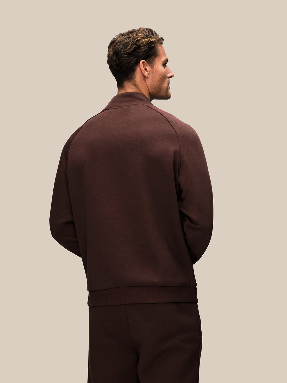 Back view of a man wearing a brown Adapt cotton fleece quarter zip sweatshirt.