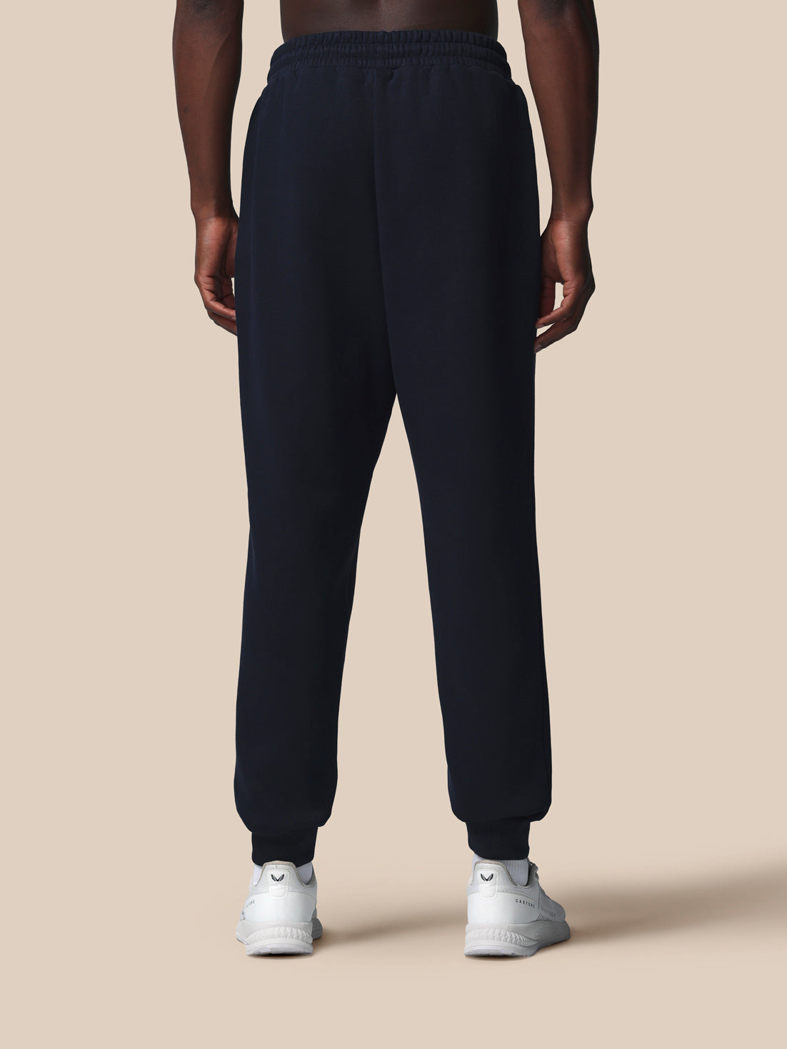 Person wearing black sweatpants on a beige background