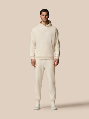 Man wearing a cream-colored hoodie and pants on a beige background