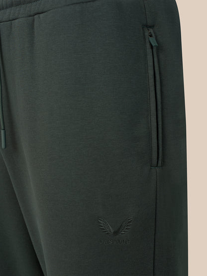 Close-up of dark gray sweatpants showing a side zip pocket, drawstring waistband, and a tonal embroidered winged logo near the lower leg.