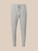 Light gray heather jogger sweatpants with an elastic waistband, drawstring, and ribbed ankle cuffs, shown against a solid beige background.