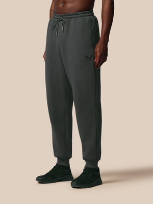 Person wearing dark gray sweatpants on a beige background