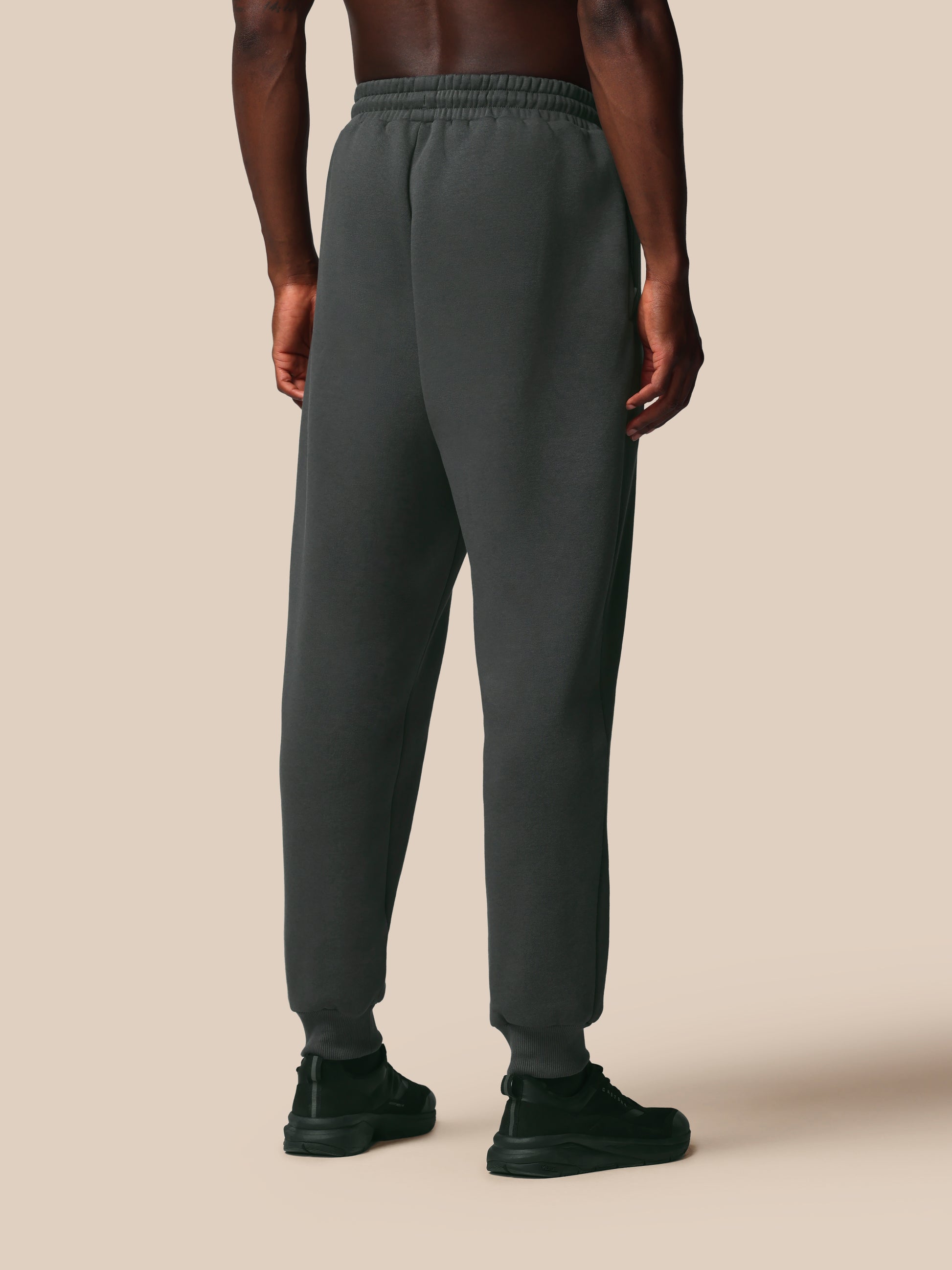 Person wearing gray sweatpants on a beige background