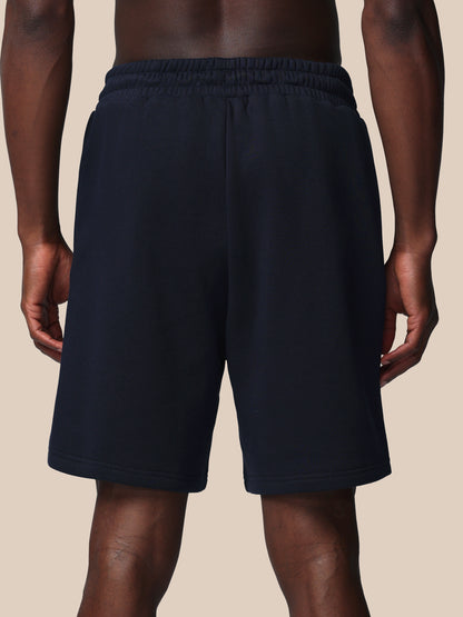 Black shorts worn by a person on a beige background