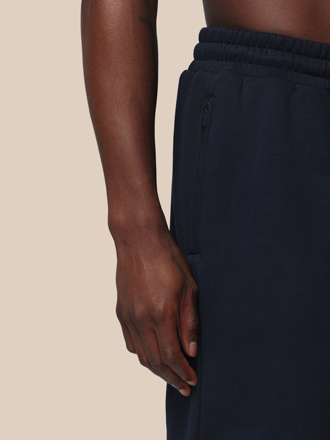 Navy blue pants worn by a person on a beige background