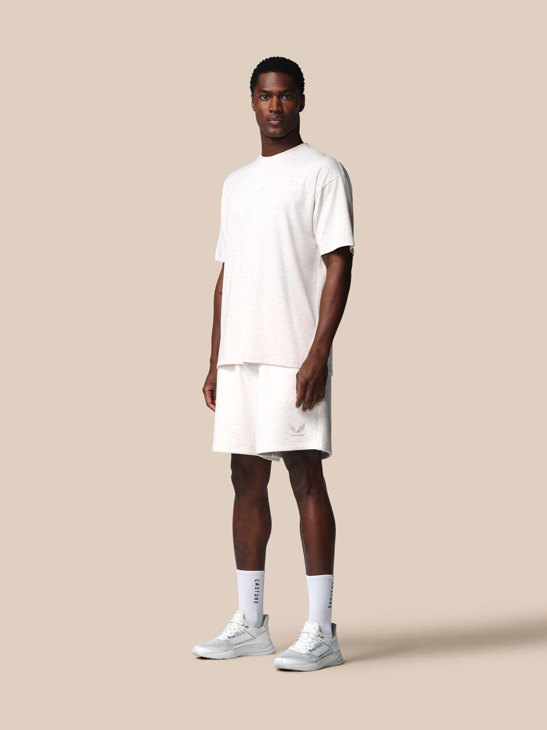 Man wearing a white t-shirt and shorts on a beige background